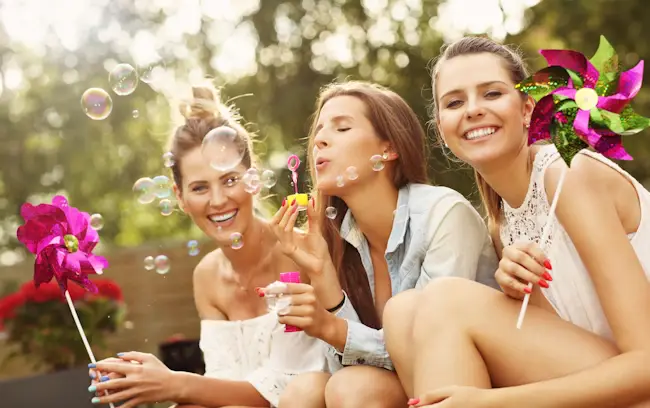 Three women enjoying a summer day and blowing bubbles.